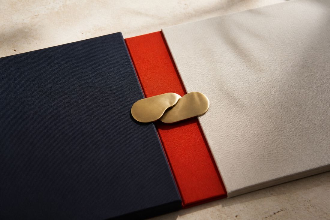 A close view of a navy, red and cream folio held shut by a brass clasp