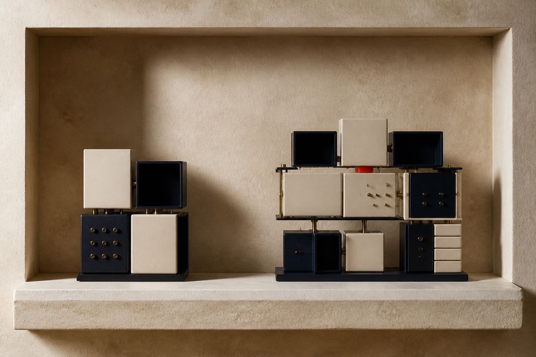 Two block structures on a wooden table separated by a red line: a compact stepped navy mass on one side, a taller open frame of glass and brass on the other